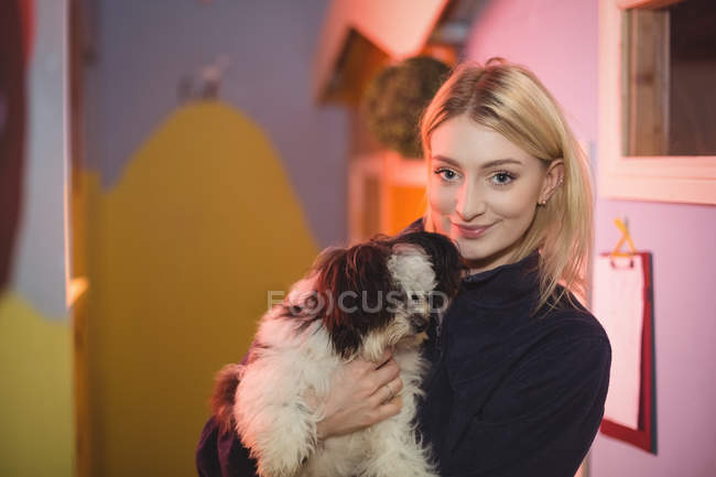 Portrait of woman carrying papillon dog at dog care center — Stock Photo