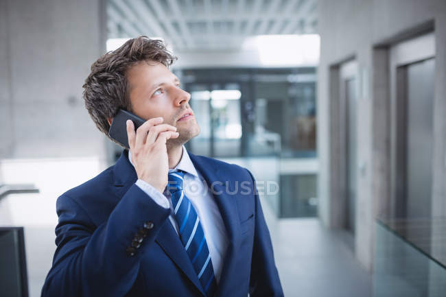 Businessman talking on mobile phone in office — Stock Photo