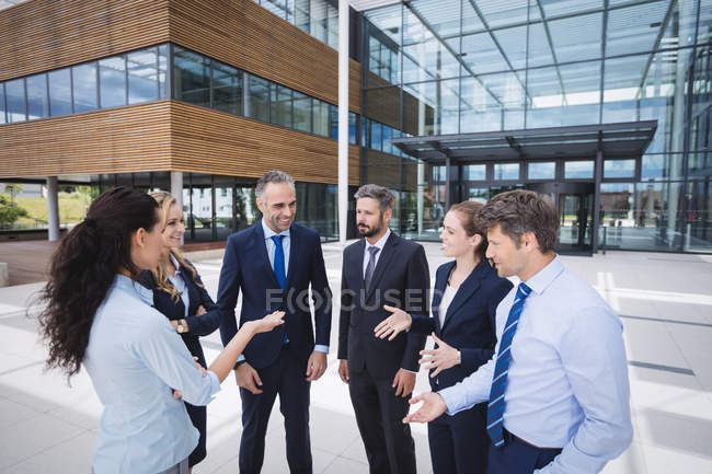 Grupo de empresários alegres interagindo fora do prédio de escritórios — Fotografia de Stock