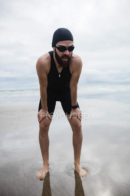 Втомлений чоловік робить перерву під час бігу на пляжі — стокове фото