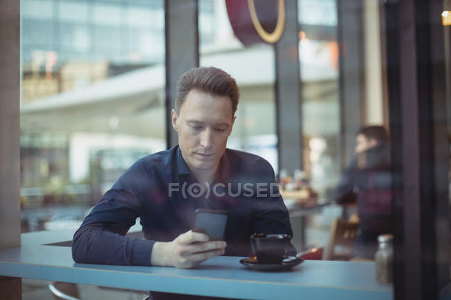 Homme cadre utilisant téléphone portable au comptoir dans la cafétéria — Photo de stock