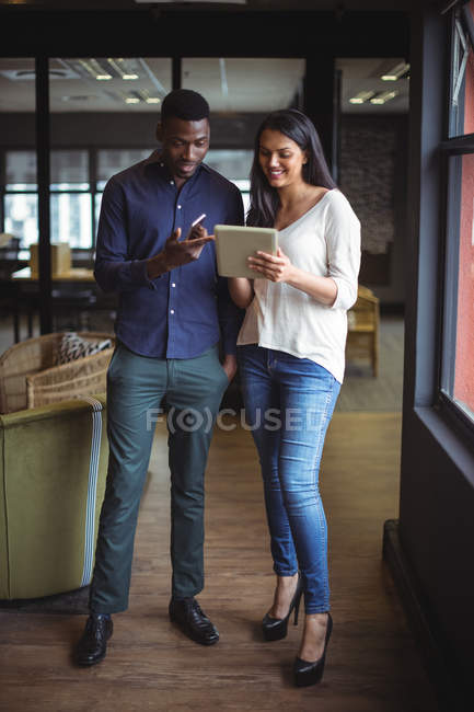 Empresário e um colega discutindo sobre tablet digital e celular no escritório — Fotografia de Stock