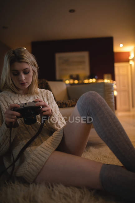 Schöne Frau beim Betrachten von Bildern auf Digitalkamera zu Hause — Stockfoto