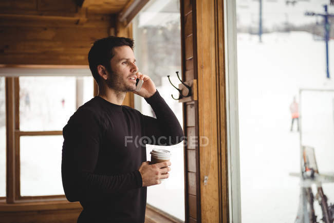 Homme au téléphone devant la fenêtre avec café — Photo de stock