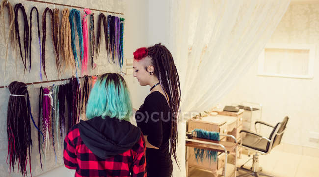Владелец женского магазина показывает дреды покупателю в магазине — стоковое фото
