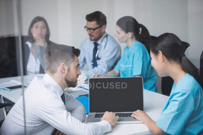 Médicos discutiendo sobre portátil en la reunión en la sala de conferencias - foto de stock