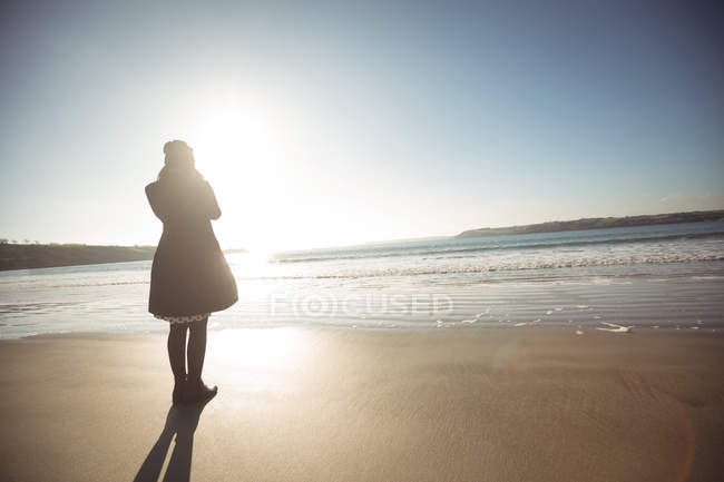 Вид сзади женщины, стоящей на пляже днем — стоковое фото