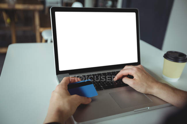 Woman making payment online using laptop and credit card in cafe — Stock Photo