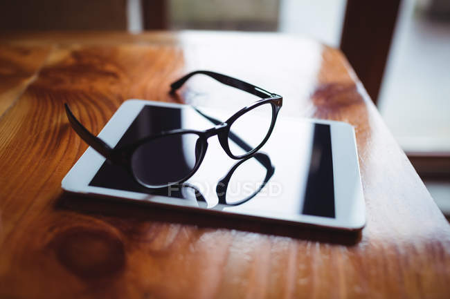Tavoletta digitale con occhiali sul tavolo nel caffè — Foto stock