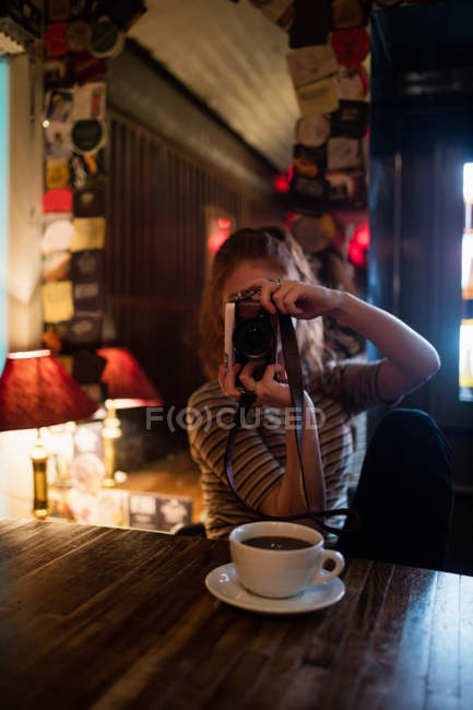 Mujer haciendo clic en una imagen con cámara en la barra - foto de stock