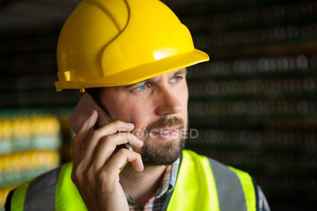 Primer plano del trabajador masculino hablando por teléfono en fábrica - foto de stock