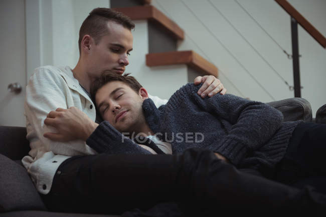 Gay casal abraçando no sofá no casa — Fotografia de Stock