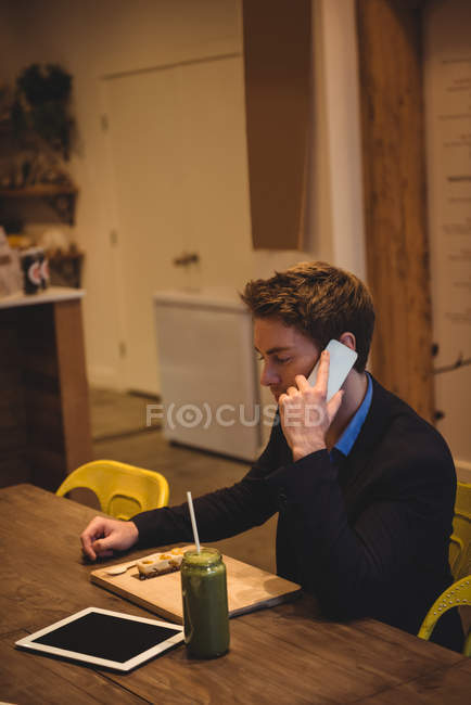 Businessman talking on mobile phone in cafe — Stock Photo