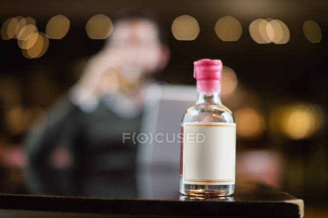 Primer plano de la pequeña botella de licor en la mesa en la barra - foto de stock