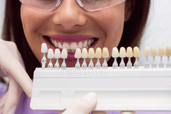 Dentista examinando paciente do sexo feminino com tons de dentes na clínica odontológica — Fotografia de Stock