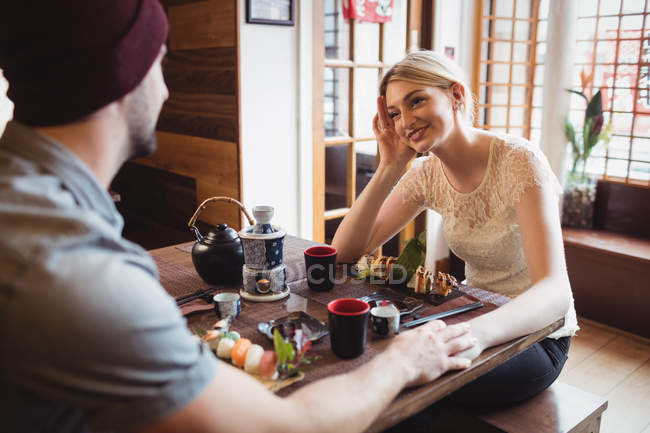 Casal interagindo uns com os outros, tendo sushi no restaurante — Fotografia de Stock