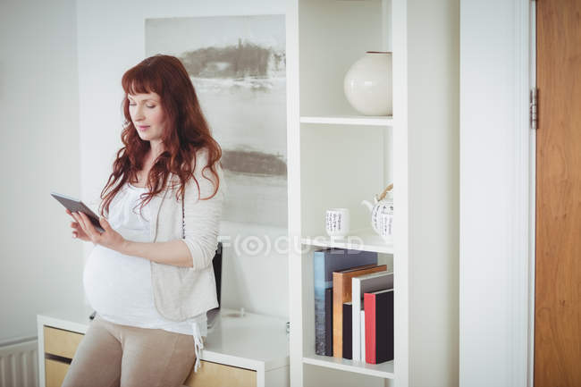 Femme enceinte utilisant une tablette numérique dans la salle d'étude à la maison — Photo de stock