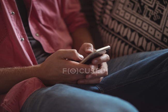 Close-up of a man holding mobile phone in living room — Stock Photo