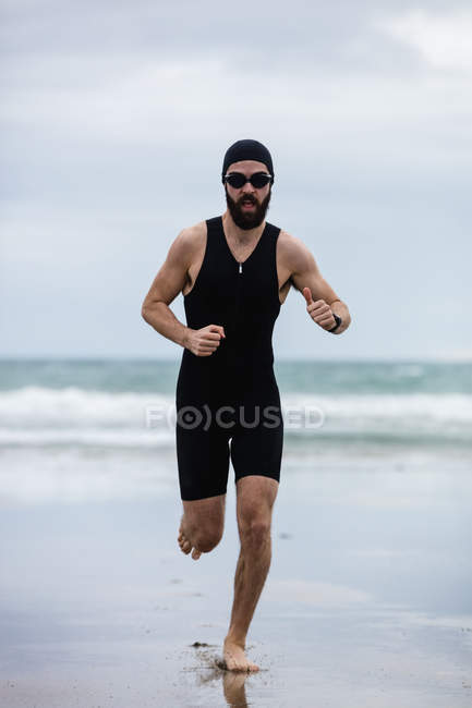 Athlète en lunettes de natation courant sur la plage — Photo de stock
