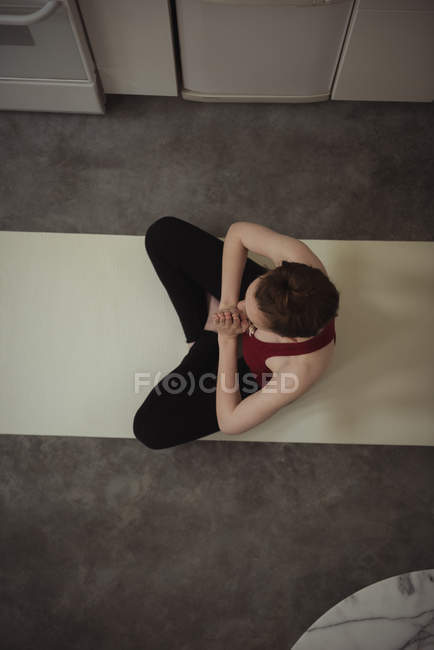 Woman performing yoga in kitchen at home, overhead view — Stock Photo