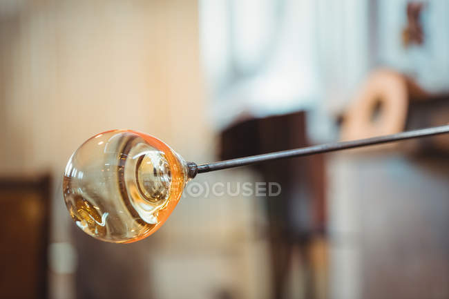 Close-up of a molten glass on blowpipe at glassblowing factory — Stock Photo