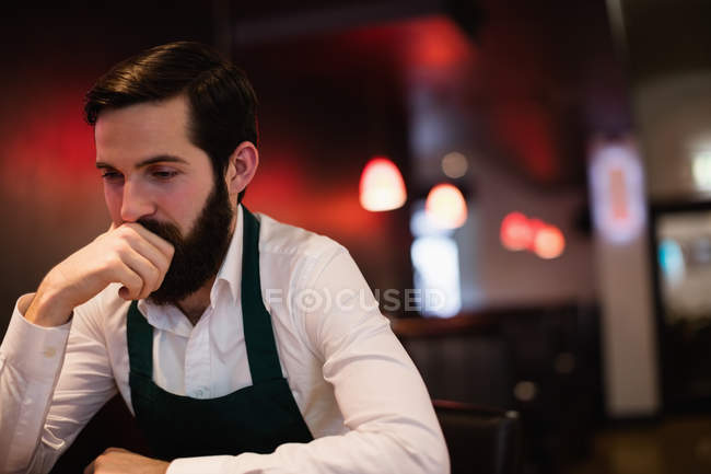 Thoughtful waiter standing near bar counter at bar — Stock Photo