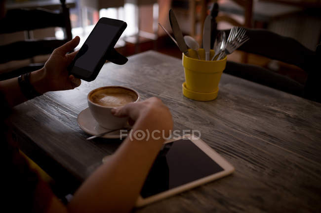 Hand of woman using mobile phone in cafe — Stock Photo