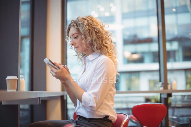 Blondine benutzt Handy am Tresen in Cafeteria — Stockfoto