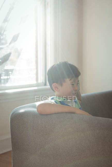 Boy sitting on sofa in living room at home — Stock Photo