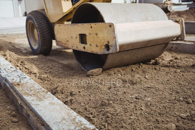 Gros plan sur la boue de nivellement des rouleaux routiers sur le chantier — Photo de stock
