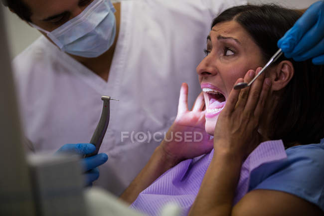 Пациентка напугана во время осмотра зубов в стоматологической клинике — стоковое фото