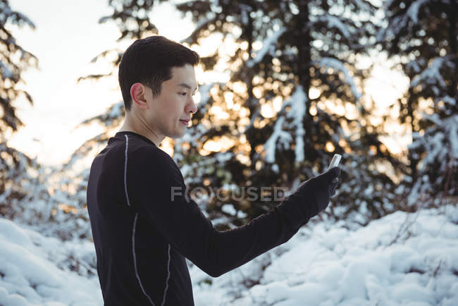 Man in warm clothing using mobile phone during winter — Stock Photo