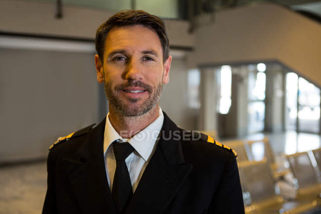 Portrait of smiling pilot standing in airport terminal — Stock Photo