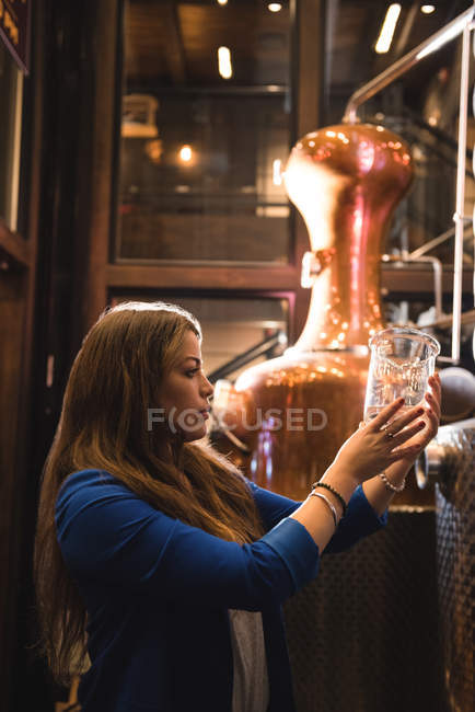 Femme tenant un bécher à mesurer dans une usine de bière — Photo de stock