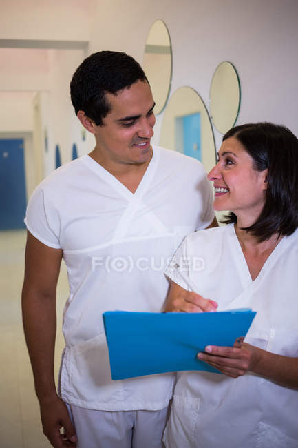 Два улыбающихся дантиста с пациентами сообщают в клинике — стоковое фото