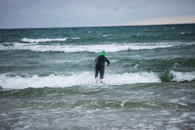 Rückansicht des Athleten im Neoprenanzug beim Tauchen im Meer — Stockfoto