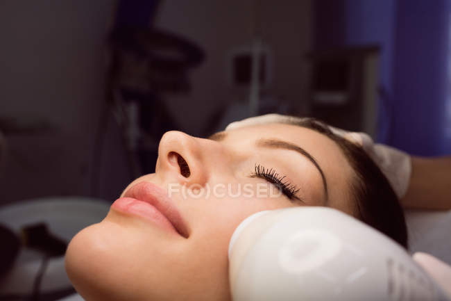 Dermatologist giving facial massage to patient through sonic lifting in clinic — Stock Photo