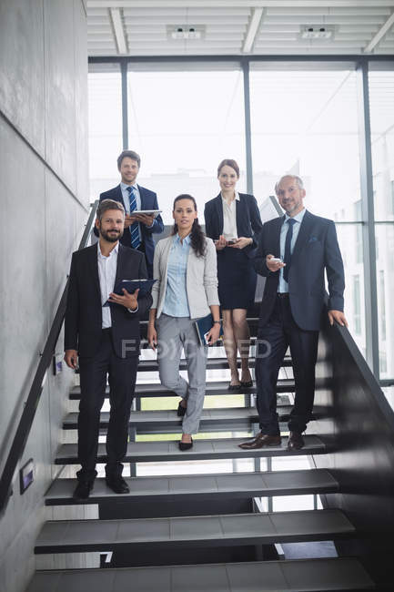Retrato de gente de negocios confiada de pie en la escalera en la oficina - foto de stock