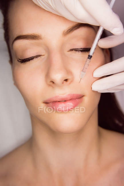 Молодая пациентка получает косметическую инъекцию на лице в эстетической клинике — стоковое фото