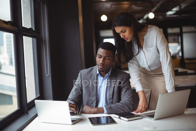 Homme d'affaires et un collègue travaillant sur ordinateur portable dans le bureau — Photo de stock