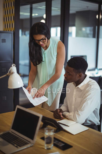 Un homme d'affaires et un collègue discutent d'un document au bureau — Photo de stock