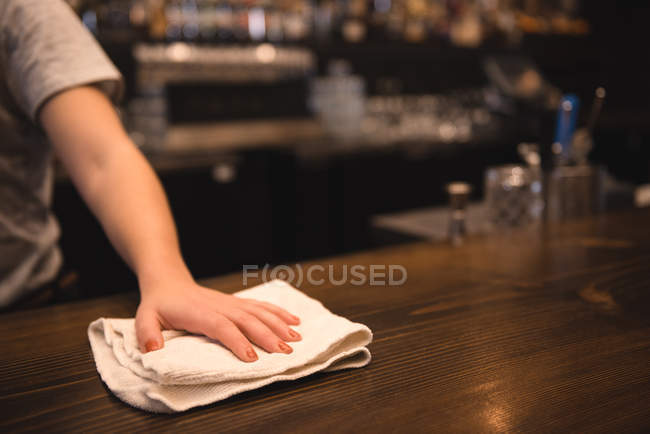 Primer plano del mostrador de la barra de limpieza del camarero usando un trapo - foto de stock