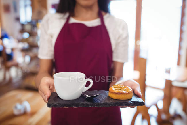 Mid-section of waitress holding a cup of coffee and snacks in super market — Stock Photo