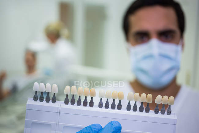 Dentist holding teeth shades in dental clinic — Stock Photo