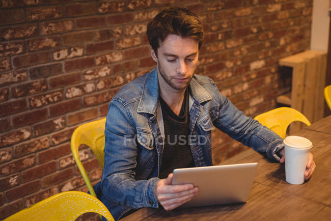 Homem usando tablet digital enquanto toma café no café — Fotografia de Stock