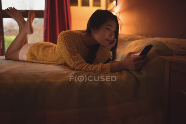 Frau lag und benutzte Handy auf Bett im heimischen Schlafzimmer — Stockfoto