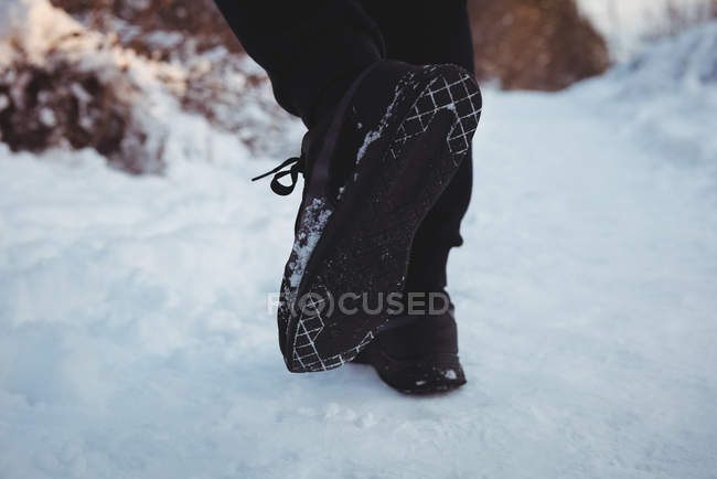 Низька частина людини біжить по засніженому шляху взимку — стокове фото