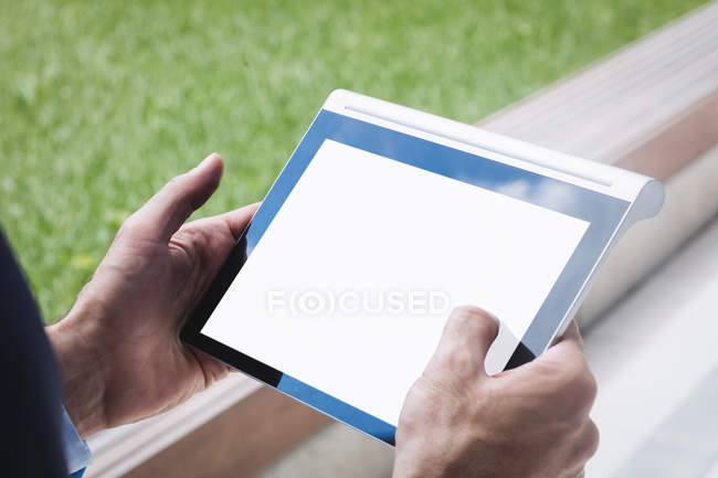 Imagen recortada de hombre de negocios utilizando tableta digital fuera del edificio de oficinas - foto de stock