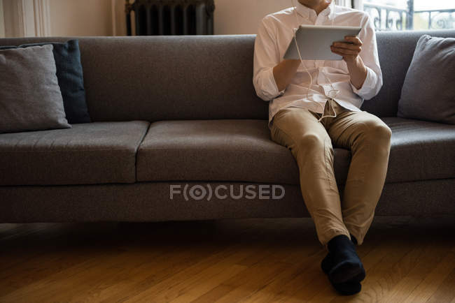 Homme écoutant de la musique sur tablette numérique à la maison — Photo de stock