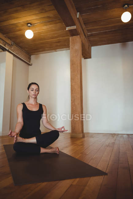 Mujer practicando yoga posición de loto en gimnasio - foto de stock